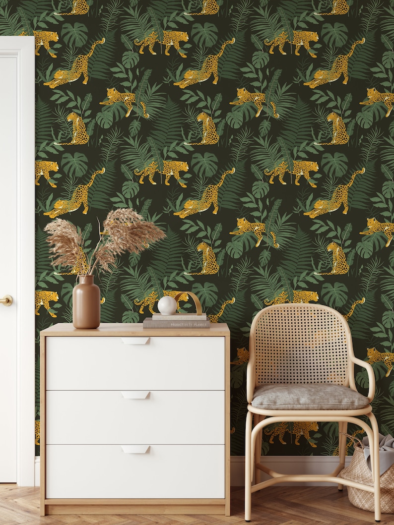 May include: A dark green wallpaper with a repeating pattern of yellow leopards and green leaves. The wallpaper is in a room with a white dresser and a wicker chair.