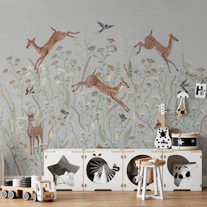 May include: A light gray nursery wallpaper with a repeating pattern of brown deer jumping through a field of green and white flowers. The wallpaper also features small black birds flying through the air. The letters "HURS" are displayed on the wall with clothespins.