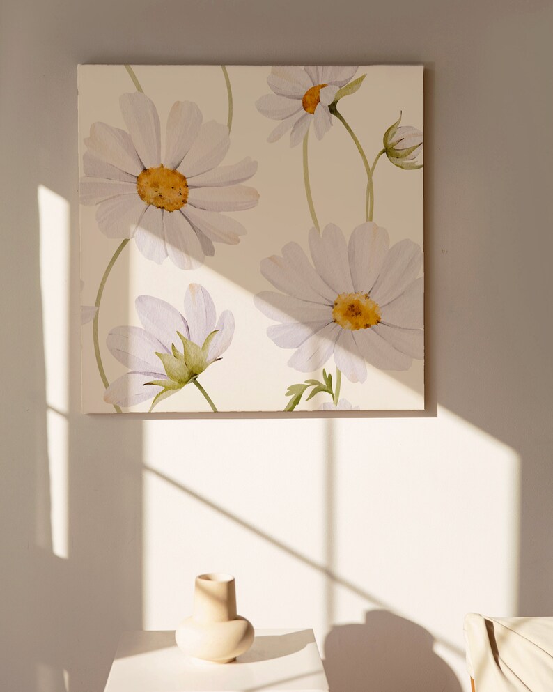 May include: A white canvas with a watercolor painting of white daisies with yellow centers. The daisies are arranged in a pattern on the canvas. The canvas is hanging on a white wall.