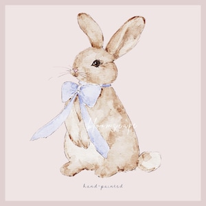 May include: A watercolor painting of a brown rabbit wearing a light blue bow. The rabbit is sitting on a light pink background. The text "hand-painted" is written below the rabbit.