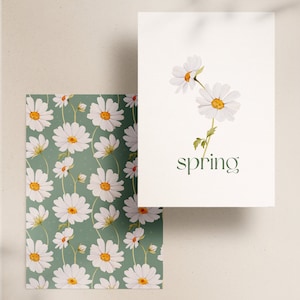 May include: A white card with a green background and the word "spring" printed in green. The card features a watercolor illustration of three white daisies with yellow centers and green stems.