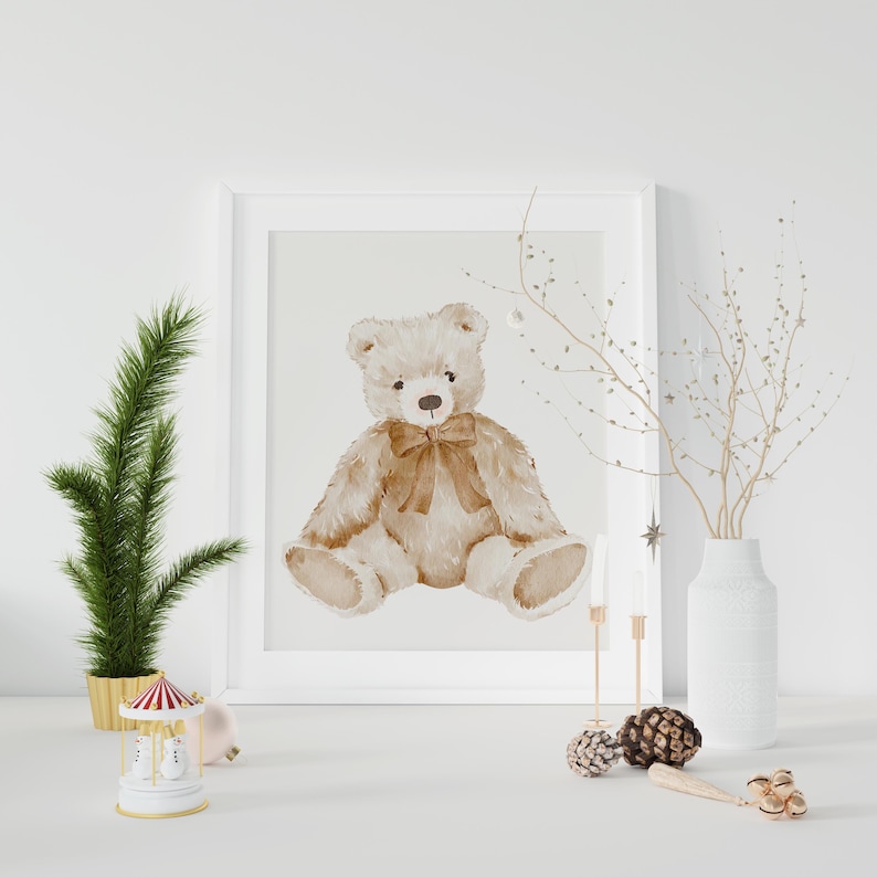 May include: A watercolor illustration of a brown teddy bear with a brown bow sitting on a white background. The illustration is framed in a white frame.