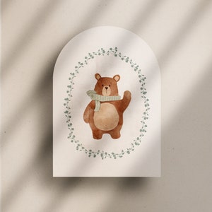 May include: A brown bear wearing a green scarf stands in a wreath of green leaves on a white background.