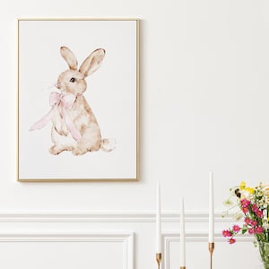 May include: A watercolor painting of a brown rabbit with a pink bow. The rabbit is sitting on a white background.