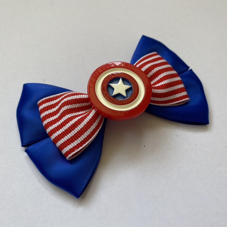 May include: A blue and red bow with a white star in the center of a red, white, and blue circle. The circle is attached to the center of the bow.