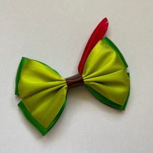 Op de afbeelding: Een groene en limoengroene satijnen strik met een bruin midden en een rode verenversiering.