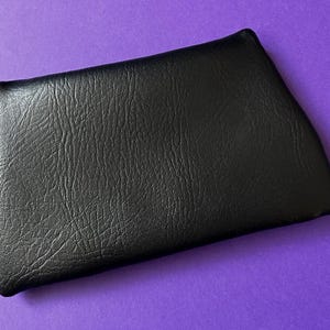 May include: A black leather wallet with a textured surface.