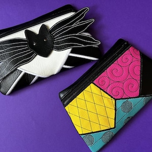 May include: Two small zippered pouches with different patterns. One pouch is black and white with a bat design. The other pouch is black with a patchwork design in yellow, pink, blue, and green.