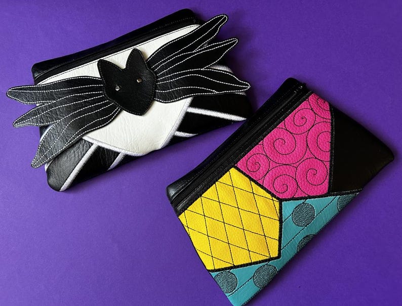 May include: Two small zippered pouches with different patterns. One pouch is black and white with a bat design. The other pouch is black with a patchwork design in yellow, pink, blue, and green.