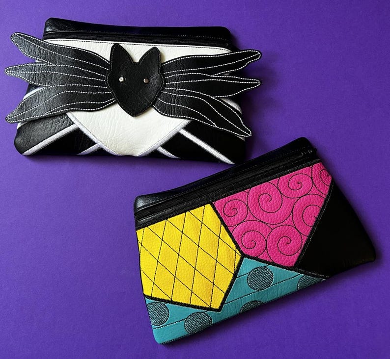 May include: Two black zippered pouches with different designs. The first pouch has a black bat with white stitching and a white background. The second pouch has a patchwork design with yellow, pink, blue, and black fabric.