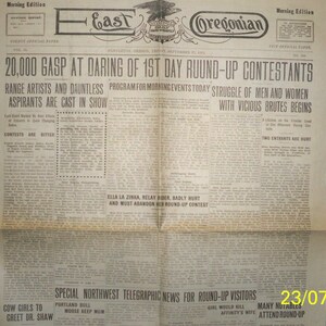 Puede incluir: Un recorte de periódico en blanco y negro del East Oregonian, fechado el 12 de septiembre de 1913, con el titular "20.000 GASP AT DARING OF 1ST DAY ROUND-UP CONTESTANTS". El artículo trata sobre los artistas de rodeo y los concursantes que participan en el evento.