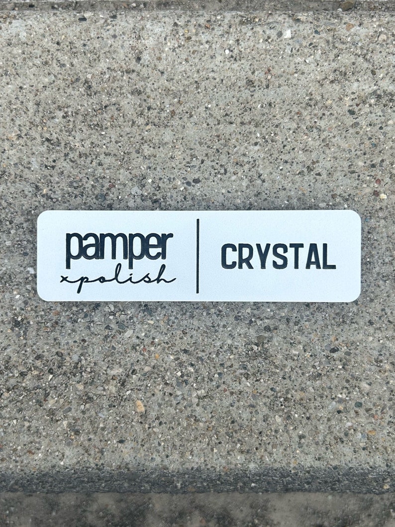 以下が含まれることがあります： 「pamper xpolish」と「CRYSTAL」という黒い文字が書かれた白い長方形のステッカーです。