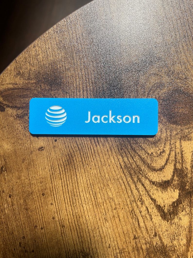 以下が含まれることがあります： 白いAT＆Tロゴと白い文字で「Jackson」と印刷された青い長方形のネームタグです。