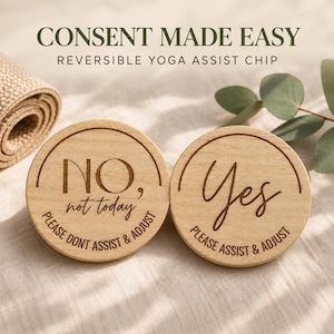 Puede incluir: Dos fichas redondas de madera con texto grabado. Una ficha dice NO, not today, PLEASE DONT ASSIST & ADJUST. La otra ficha dice Yes, PLEASE ASSIST & ADJUST. El texto CONSENT MADE EASY REVERSIBLE YOGA ASSIST CHIP se ve sobre las fichas.