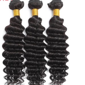 May include: Three bundles of black human hair extensions in a deep wave texture. The hair is tied with a gold elastic band at the top.