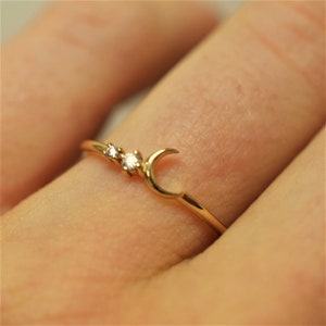 May include: A gold ring with a crescent moon design and two small diamonds.