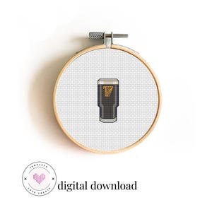 May include: A cross-stitch embroidery hoop featuring a pint of stout with a gold logo. The design is set against a white background and is held in a wooden embroidery hoop. The text "digital download" is also included.
