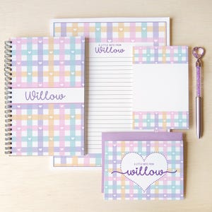 May include: A stationery set featuring a spiral-bound notebook, a lined notepad, a blank notepad, and a greeting card, all with a pastel plaid pattern and small white hearts. The text "A little note from Willow" and "Willow" appears on the items.