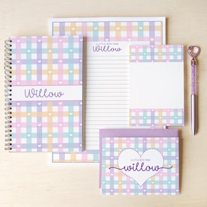 May include: A stationery set featuring a notebook, notepad, notecards, and pen. The set has a pastel plaid pattern with hearts and the name "Willow". The pen has a heart-shaped top.