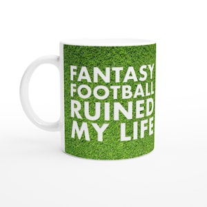 Könnte beinhalten: Weiße Keramiktasse mit grünem Gras Hintergrund und dem Text "Fantasy Football Ruined My Life" in Weiß.