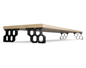 Op de afbeelding: Een modern houten plank met een lichtgekleurde houten bovenkant. De plank wordt ondersteund door zwarte, geometrische, honingraatvormige poten. Het ontwerp is minimalistisch en eigentijds, geschikt voor diverse interieurstijlen.
