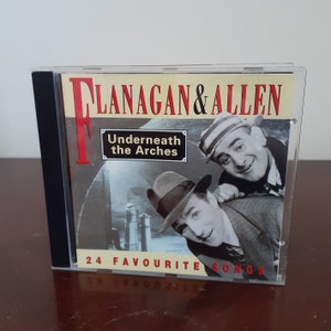 May include: A CD case with a red and white design featuring a photo of two men. The title of the album is "Flanagan & Allen Underneath the Arches 24 Favourite Songs".