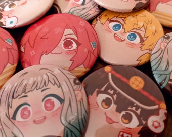 May include: A collection of colorful anime-style character buttons. The buttons feature various characters with different expressions and hairstyles. The buttons are round and have a white background with black outlines.