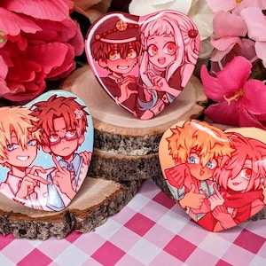 以下が含まれることがあります： アニメのキャラクターが描かれたハート型のピンが4つ。ピンはカラフルで、さまざまな髪型と表情のキャラクターが描かれています。