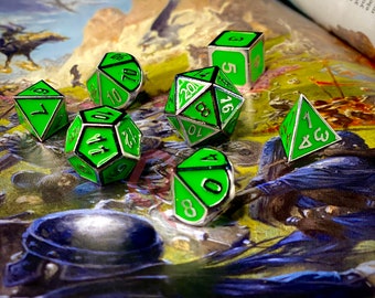 May include: A set of seven green and silver metal dice with white numbers. The dice are scattered on a book with a fantasy illustration.