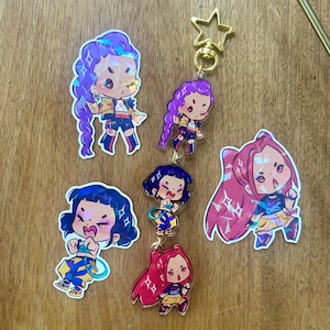 May include: A collection of colorful anime-style character keychains. The keychains feature various characters with different hairstyles and outfits. One keychain has a gold star-shaped clasp.
