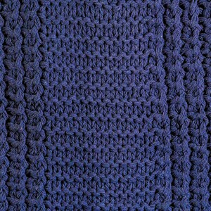 May include: Close-up of a blue knitted fabric with a textured pattern. The fabric is made of thick yarn and has a soft, cozy feel.