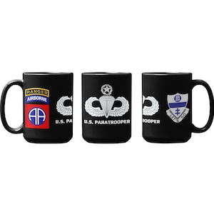 May include: Three black coffee mugs with different military insignia designs. The first mug has a Ranger Airborne emblem with the text "Ranger Airborne" and "U.S. PA". The second mug has a U.S. Paratrooper emblem with the text "U.S. Paratrooper". The third mug has a Let's Go Coopers emblem with the text "Let's Go Coopers".