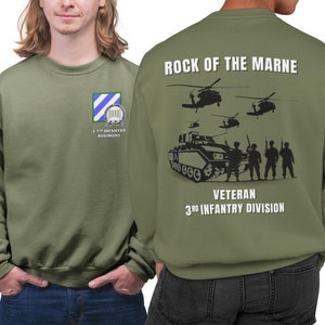 May include: A green sweatshirt with a black and white graphic on the back. The graphic features a tank, soldiers, and helicopters. The text on the back reads "Rock of the Marne" and "Veteran 3rd Infantry Division". The front of the sweatshirt has a patch with the text "2-7th Infantry Regiment".