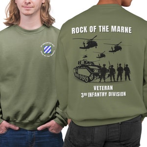 May include: Green sweatshirt with a white graphic on the back that says "Rock of the Marne" with a tank, soldiers, and helicopters. The front of the sweatshirt has a small patch with the text "3rd Infantry Div. Rock of the Marne".