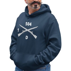 May include: A navy blue hooded sweatshirt with a white graphic of crossed rifles and the text "1 504 D".
