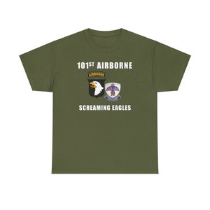 May include: A green t-shirt with the text "101st Airborne" and "Screaming Eagles" in white. The shirt features a black and white eagle insignia with the text "Airborne" and a blue, red, and white insignia with the text "101st Airborne".