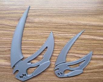 May include: Two gray plastic Mandalorian symbol ornaments. The larger ornament is about 10 inches tall and the smaller ornament is about 5 inches tall.
