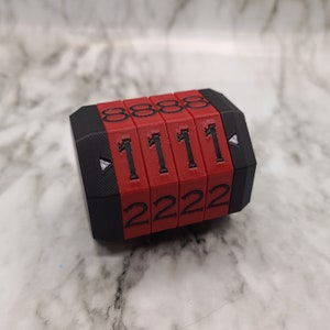 Può includere: Un lucchetto a combinazione rosso e nero con quattro quadranti. Ogni quadrante ha numeri da 0 a 9. La combinazione attuale è 8888, 1111, 2222.