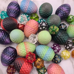 May include: A collection of colorful, textured, and patterned dice with numbers on each side. The dice are arranged in a random pattern on a white surface.