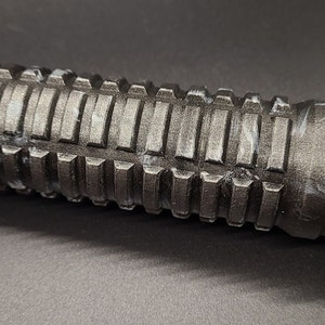 Pu&ograve; includere: Primo piano di un'impugnatura testurizzata nera con accenti bianchi. L'impugnatura ha un design rigato ed &egrave; realizzata in un materiale resistente.