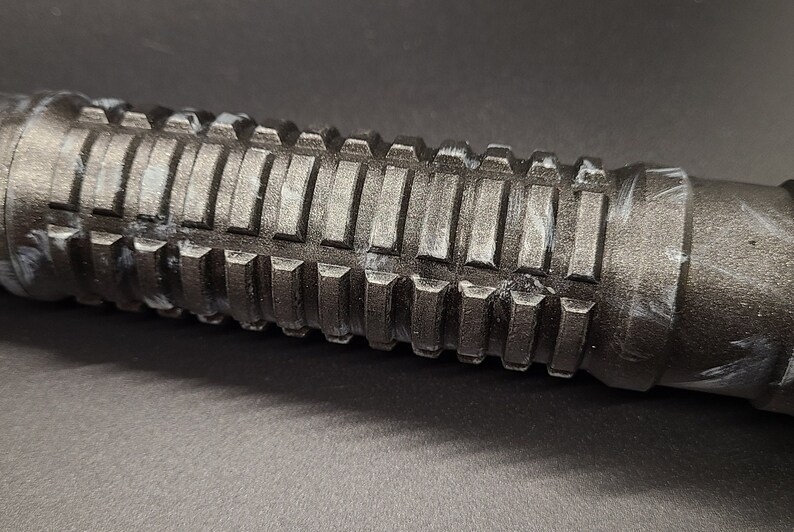 Pu&ograve; includere: Primo piano di un'impugnatura testurizzata nera con accenti bianchi. L'impugnatura ha un design rigato ed &egrave; realizzata in un materiale resistente.