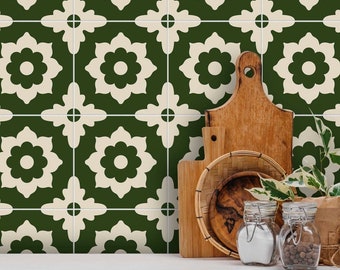 Puede incluir: Una encimera de cocina con un salpicadero de azulejos con estampado verde y blanco. La encimera es blanca y tiene una tabla de cortar de madera, una cesta de mimbre y dos tarros de vidrio con tapas.