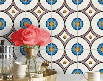 May include: A wall covered in square tiles featuring a repeating pattern of blue flowers with yellow centers, framed by dark gray curved lines and small orange dots on a white background, with a gold tray holding mugs and roses in the foreground.