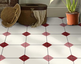 May include: A white tiled floor with a red and pink diamond pattern. A wicker suitcase and a straw hat are on the floor. A potted plant is in the background.