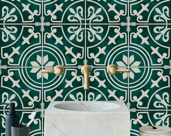 Puede incluir: Un lavabo de porcelana blanca con una cuenca redonda se asienta sobre una encimera con un salpicadero de azulejos con estampado verde y blanco. Dos grifos dorados están montados en la pared sobre el lavabo.