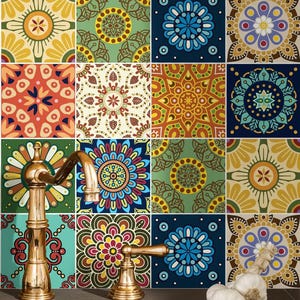 May include: A brass faucet with a curved spout and a single handle sits in front of a wall covered in square tiles featuring various colorful mandala patterns in shades of blue, yellow, red, green, and brown. A bulb of garlic rests on the counter.