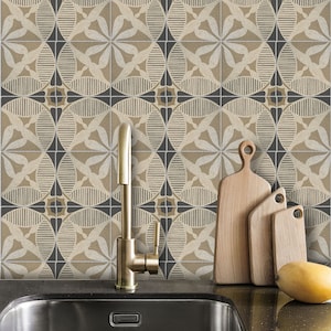 May include: A kitchen sink with a gold faucet and a black countertop. The backsplash is tiled with a geometric pattern in beige and black. Three wooden cutting boards are leaning against the backsplash.
