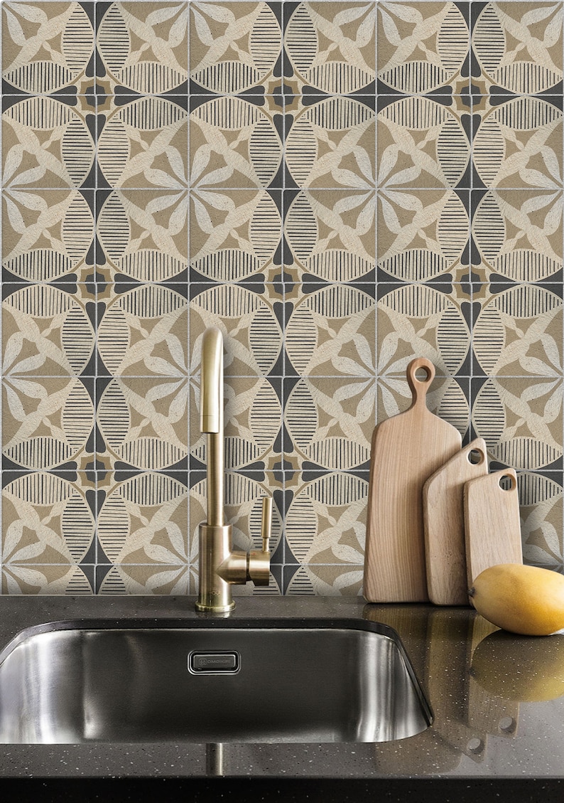 May include: A kitchen sink with a gold faucet and a black countertop. The backsplash is tiled with a geometric pattern in beige and black. Three wooden cutting boards are leaning against the backsplash.