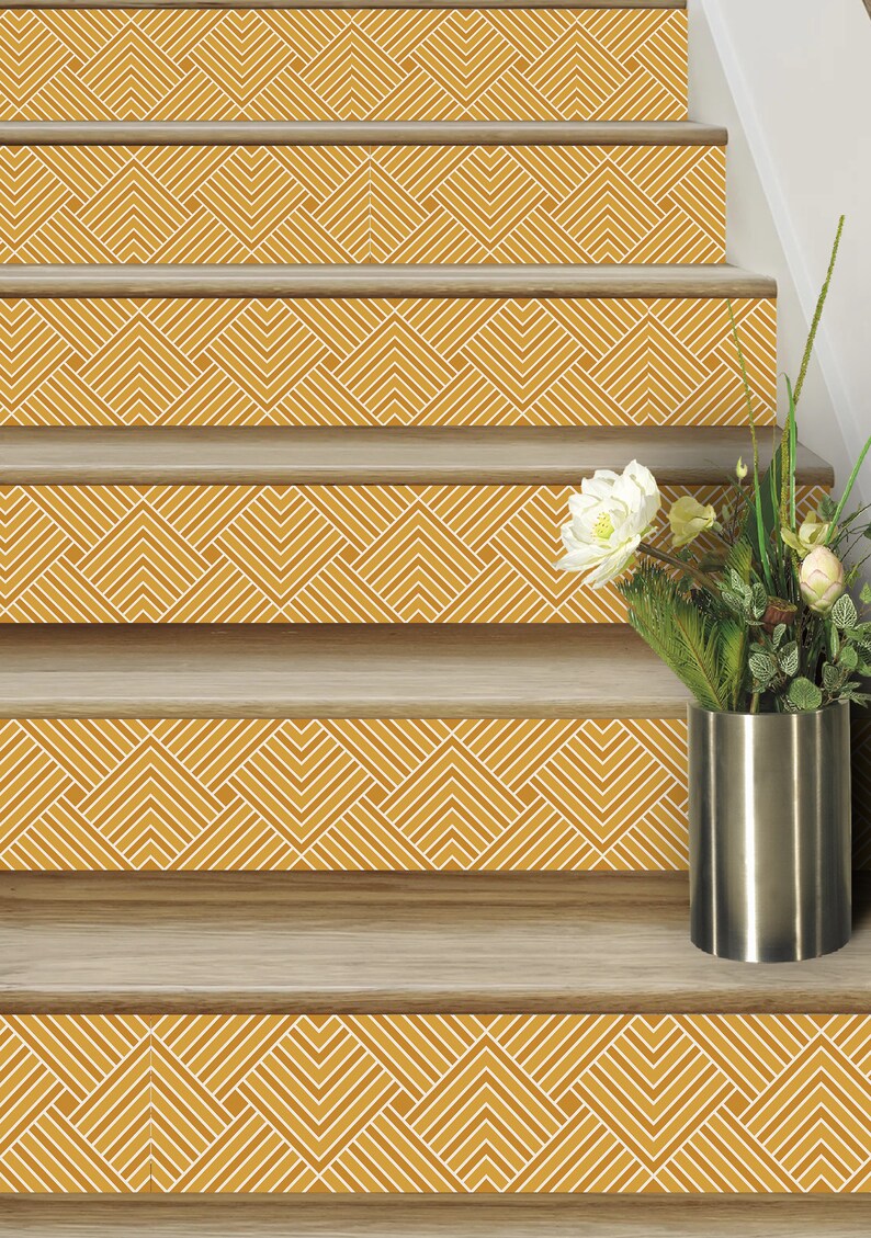 May include: A set of five stair treads with a geometric pattern in shades of yellow and white. The treads are made of wood and have a smooth finish. A vase with a white flower and green foliage is on the top step.