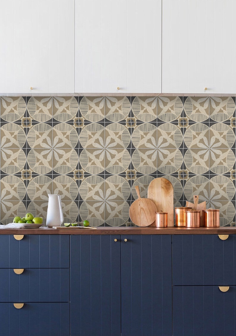 May include: A kitchen with white cabinets and a backsplash of patterned ceramic tiles. The countertop is wood and has a white pitcher, green apples, and copper canisters. The lower cabinets are dark blue with gold handles.